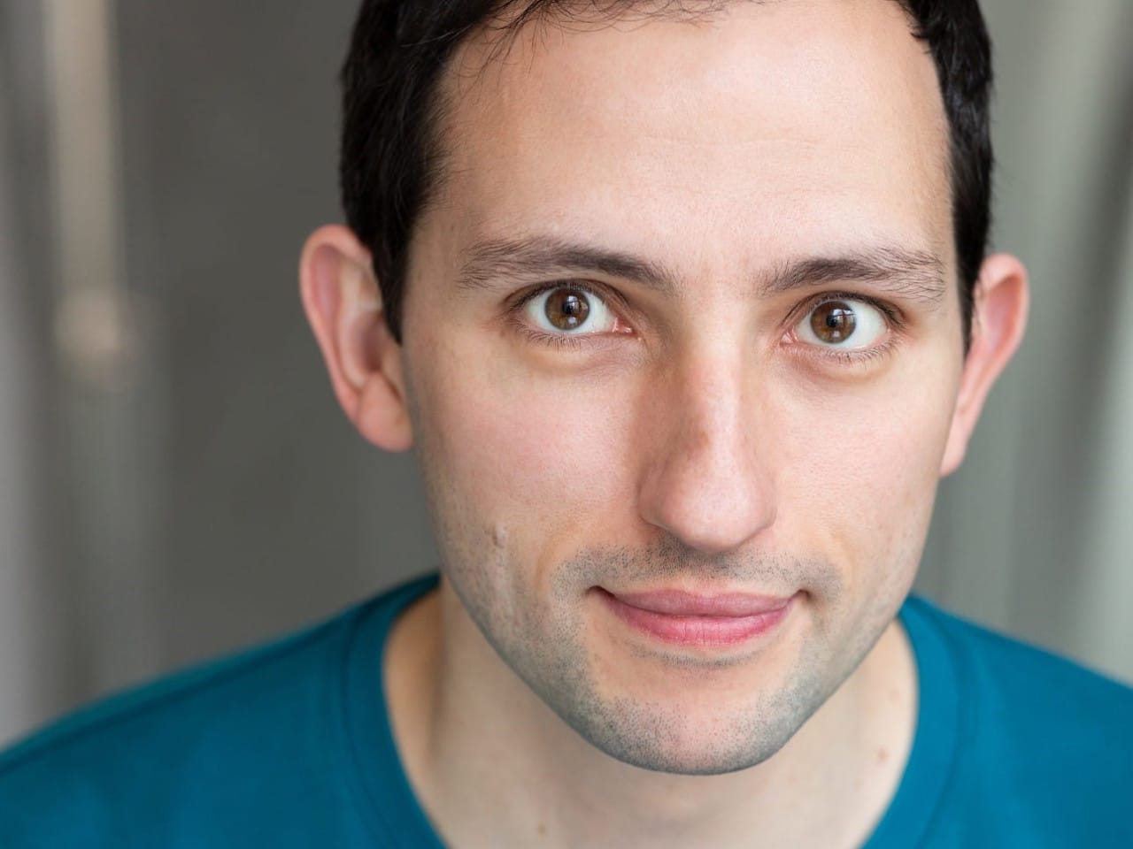 Cast headshot of performer with black hair in a blue top