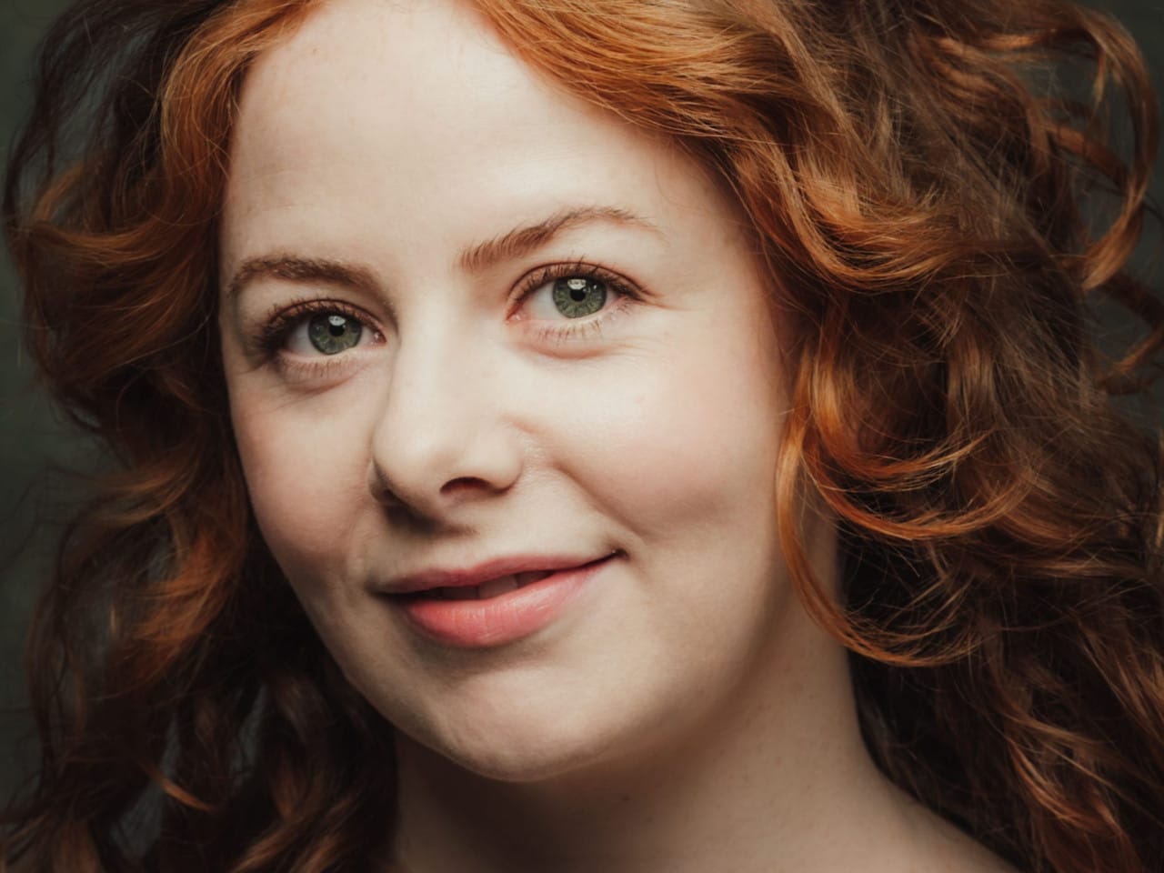 Performer’s headshot - ginger long curly hair with green top